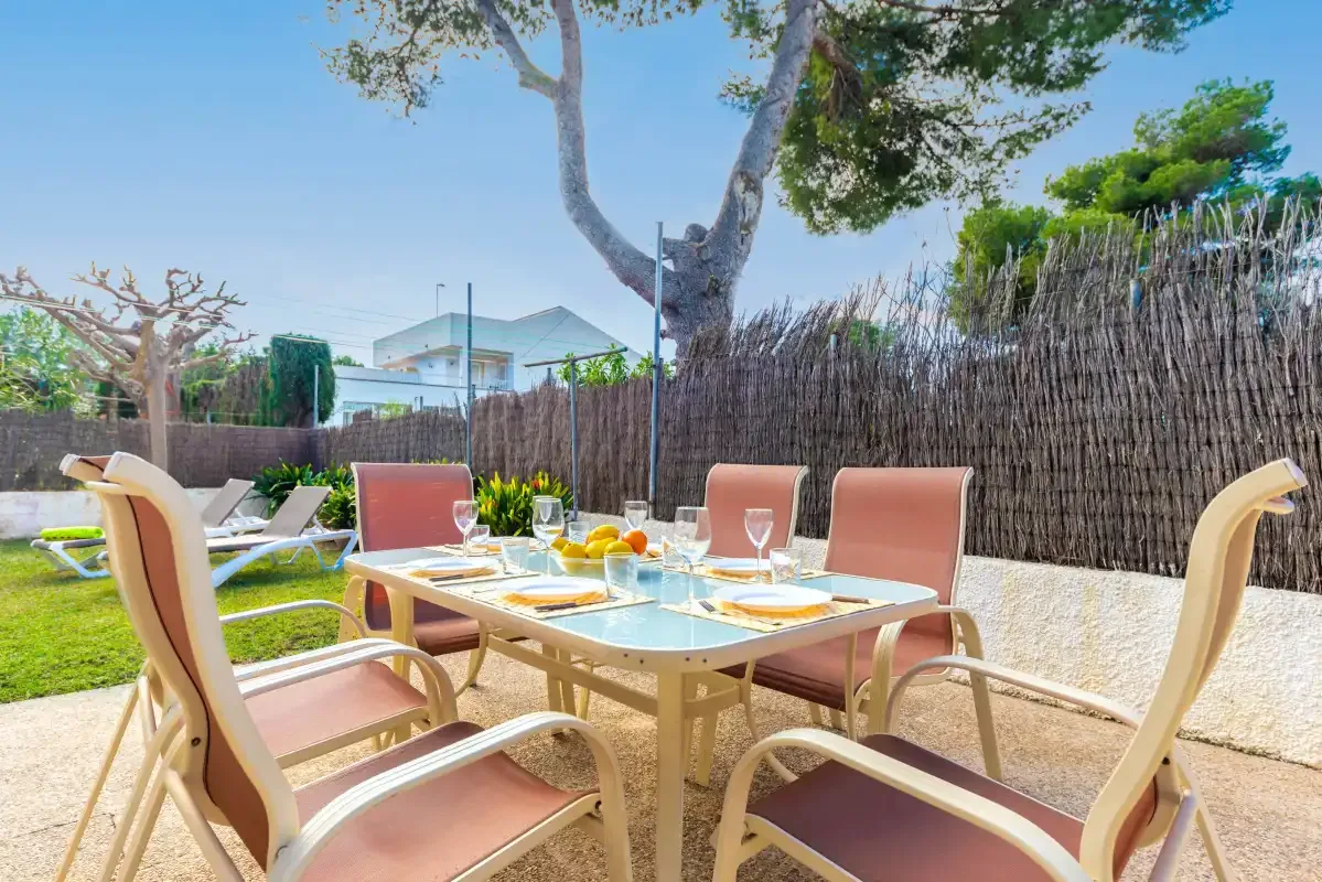An outdoor dining area with a glass-top table and cushioned seating.
