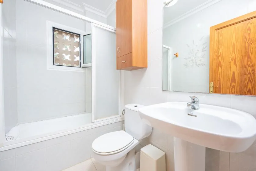 A bright bathroom with a bathtub, sink, and wall cabinet.