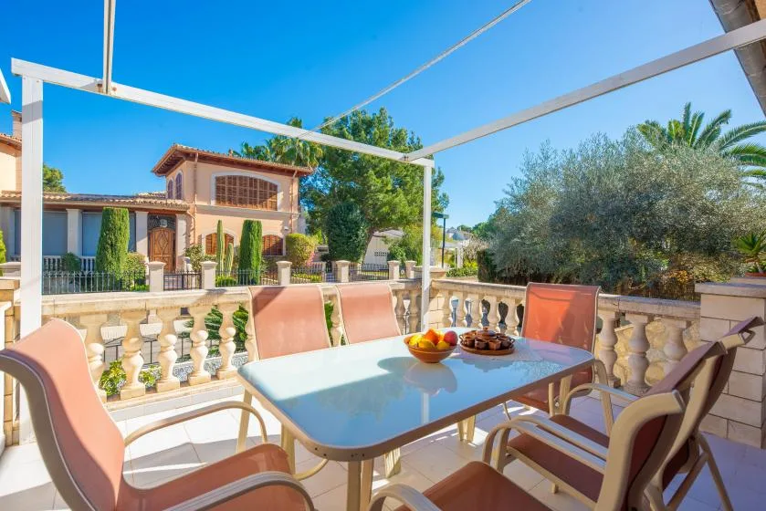 An outdoor terrace has a dining table and seating overlooking a garden.