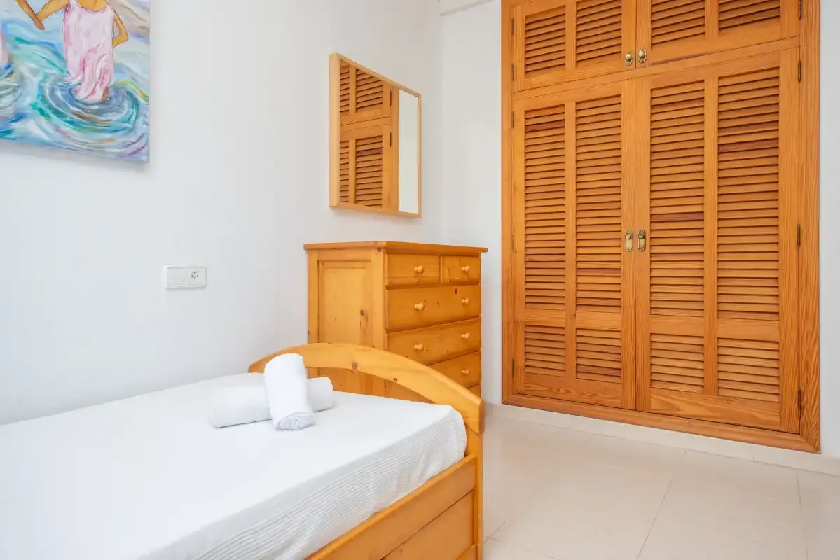 A bedroom with a bed and wooden storage cabinets.