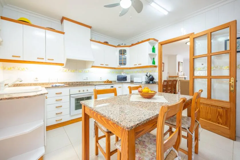 A bright kitchen and dining area with white cabinets and a wooden table.