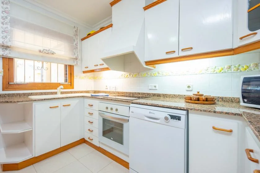 A bright kitchen with white cabinetry, a countertop, and built-in appliances.