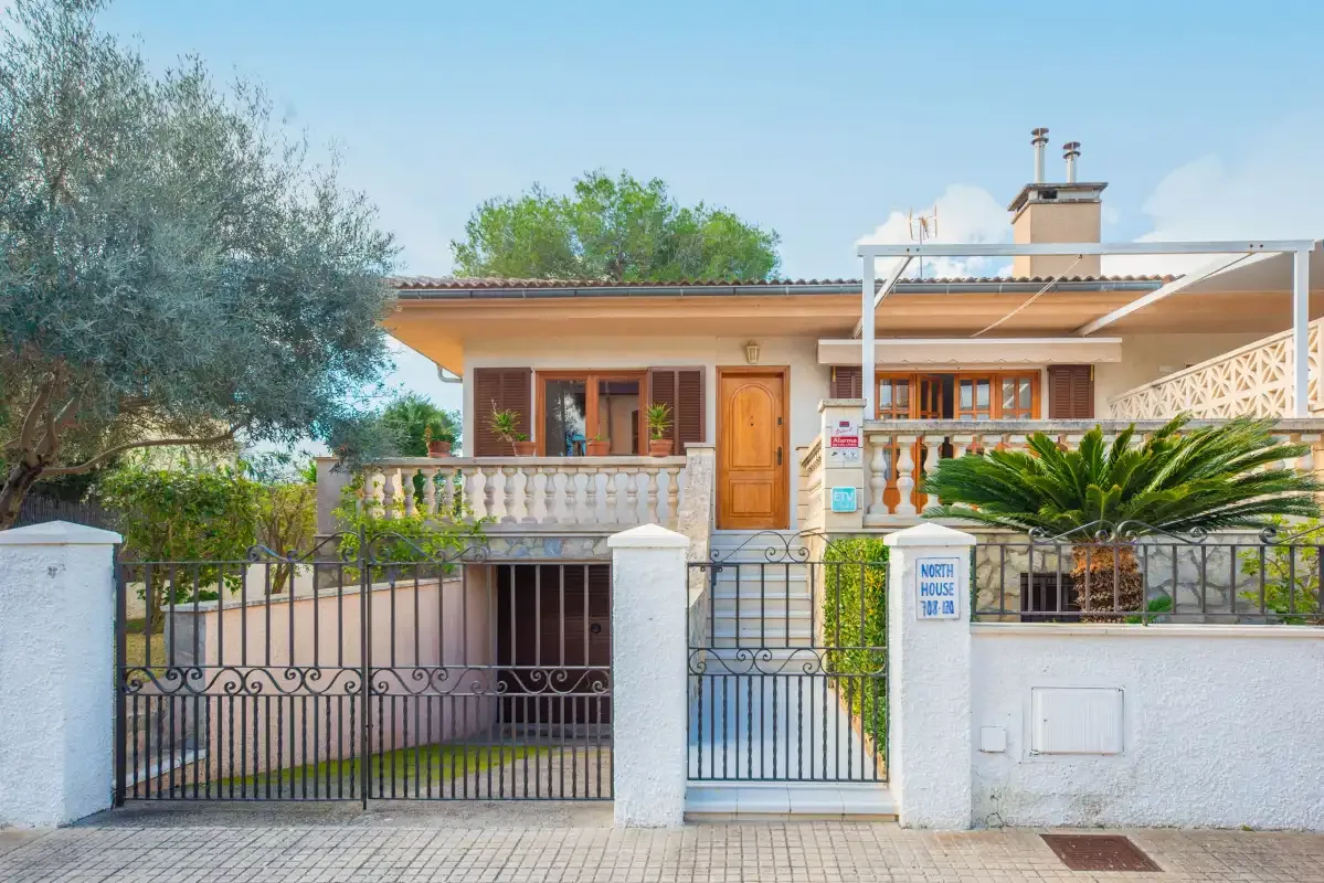 A house facade with a gated entrance and a covered terrace.