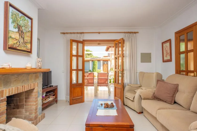 A bright living room with seating, a fireplace, and open doors to a sunny terrace.