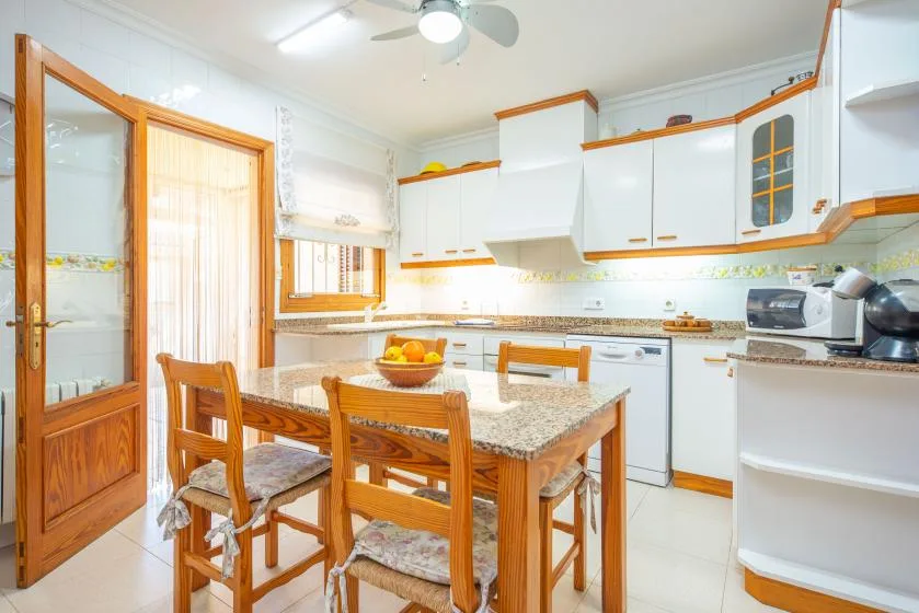 A bright kitchen with a wooden dining table and white cabinetry.