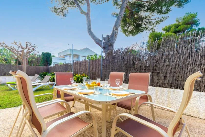 An outdoor dining area with a glass-topped table and cushioned seating.
