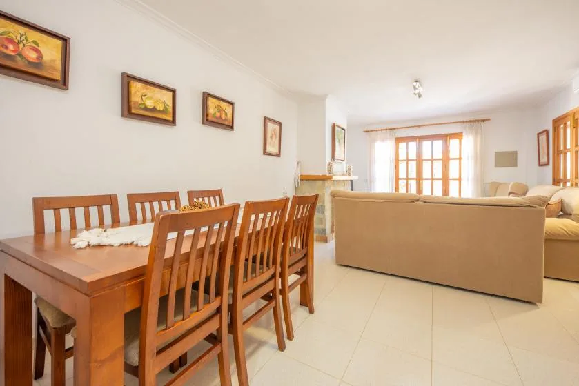 A bright living and dining area has a wooden dining table and beige seating.