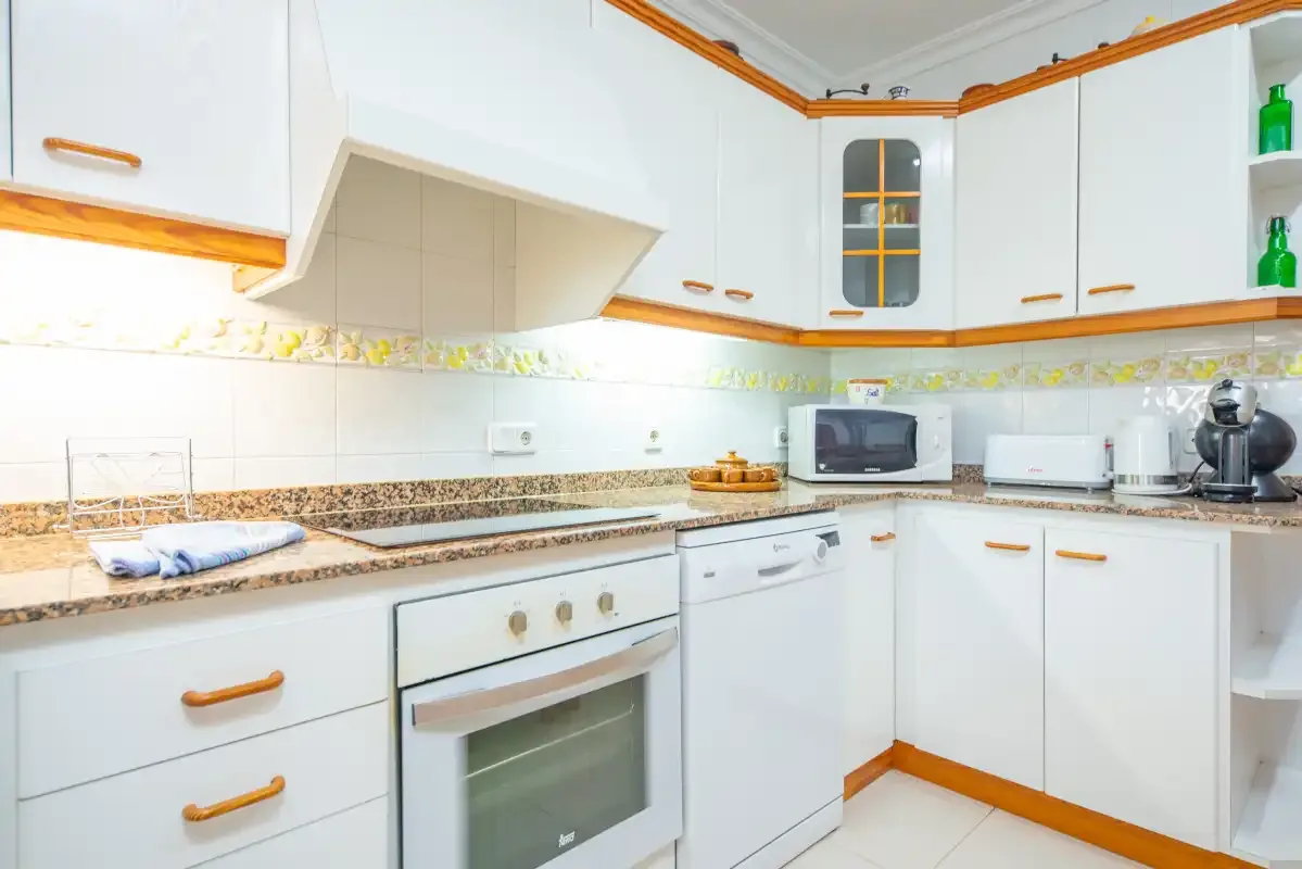 A bright kitchen with white cabinets, a countertop, and built-in cooking appliances.