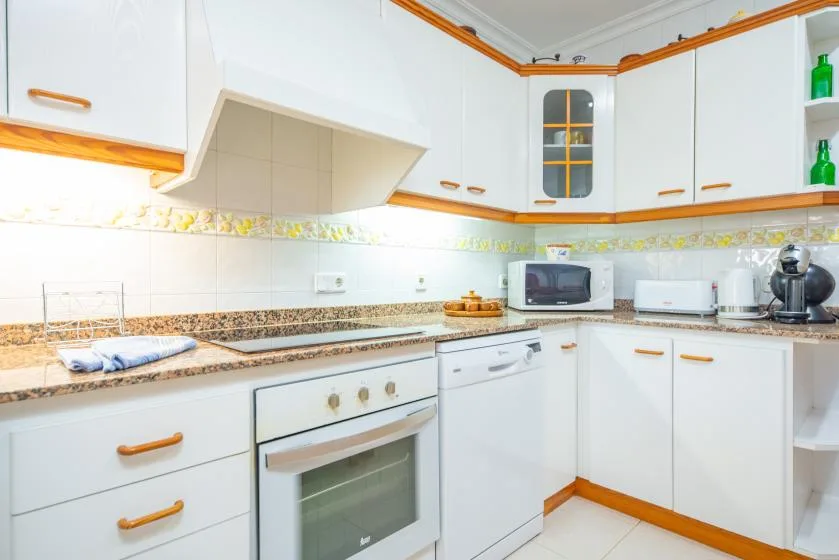 A bright kitchen with white cabinets, a countertop, and a built-in oven.