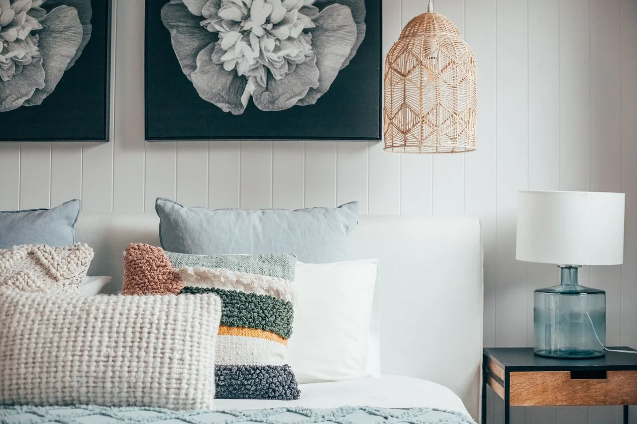 Un dormitorio con una cama, arte floral en la pared y una lámpara de noche.