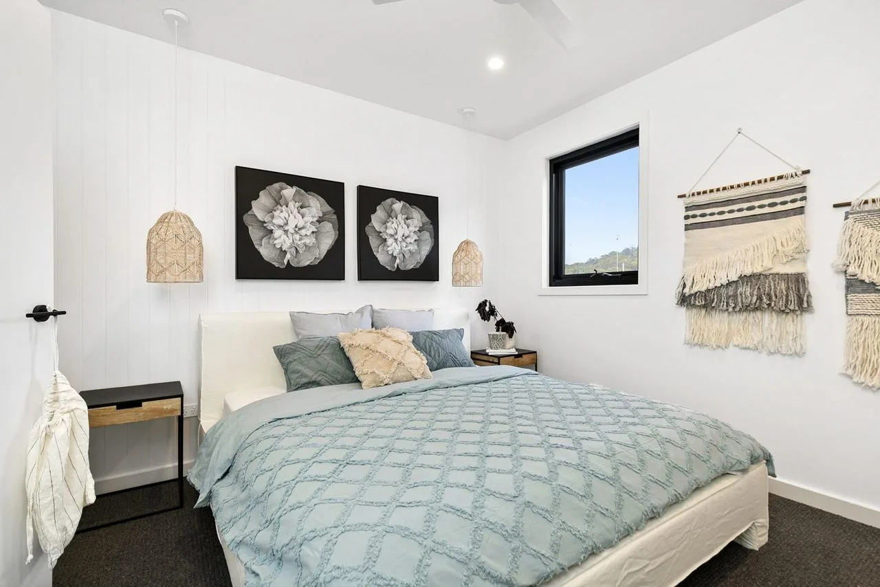 Un dormitorio con una cama, cojines decorativos y tapices tejidos.