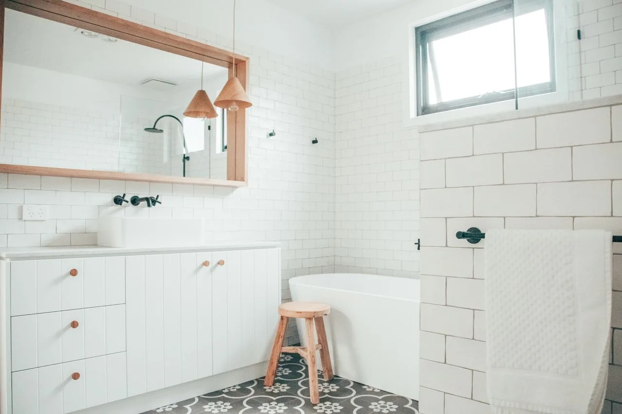 Un baño luminoso con bañera, paredes de azulejos y un espejo grande.