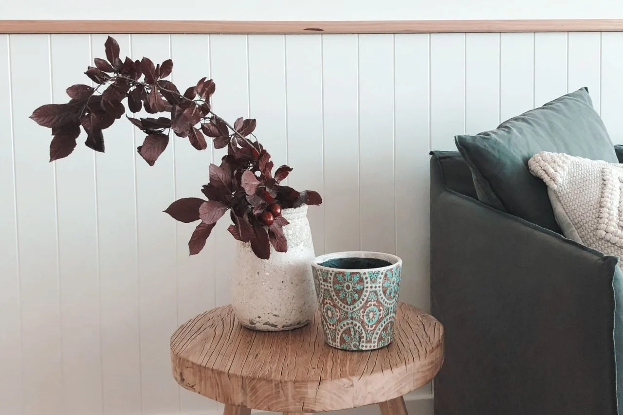 A small wooden side table with potted plants beside a dark sofa.