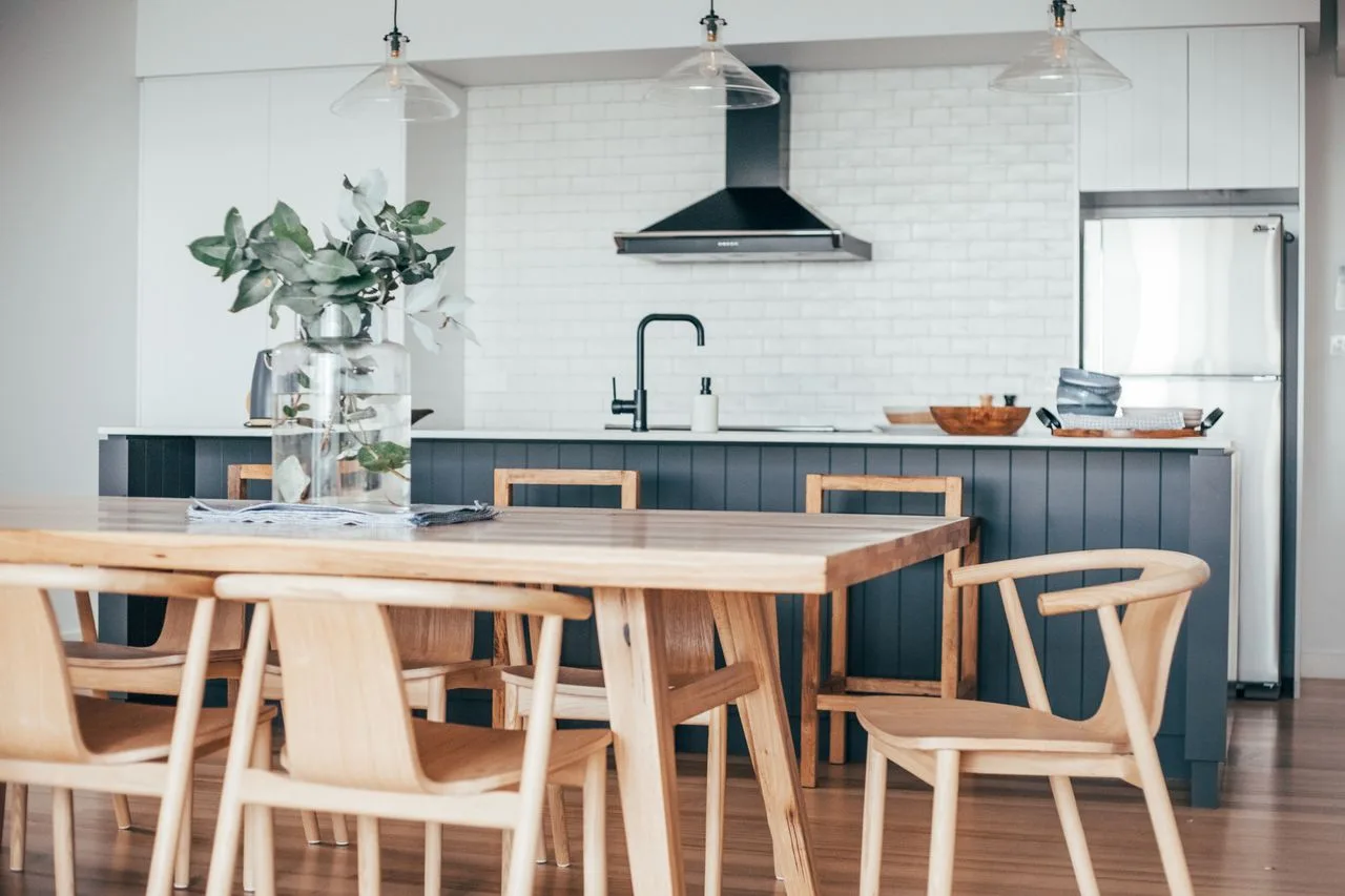 Una cocina luminosa con comedor, mesa de madera y encimera.