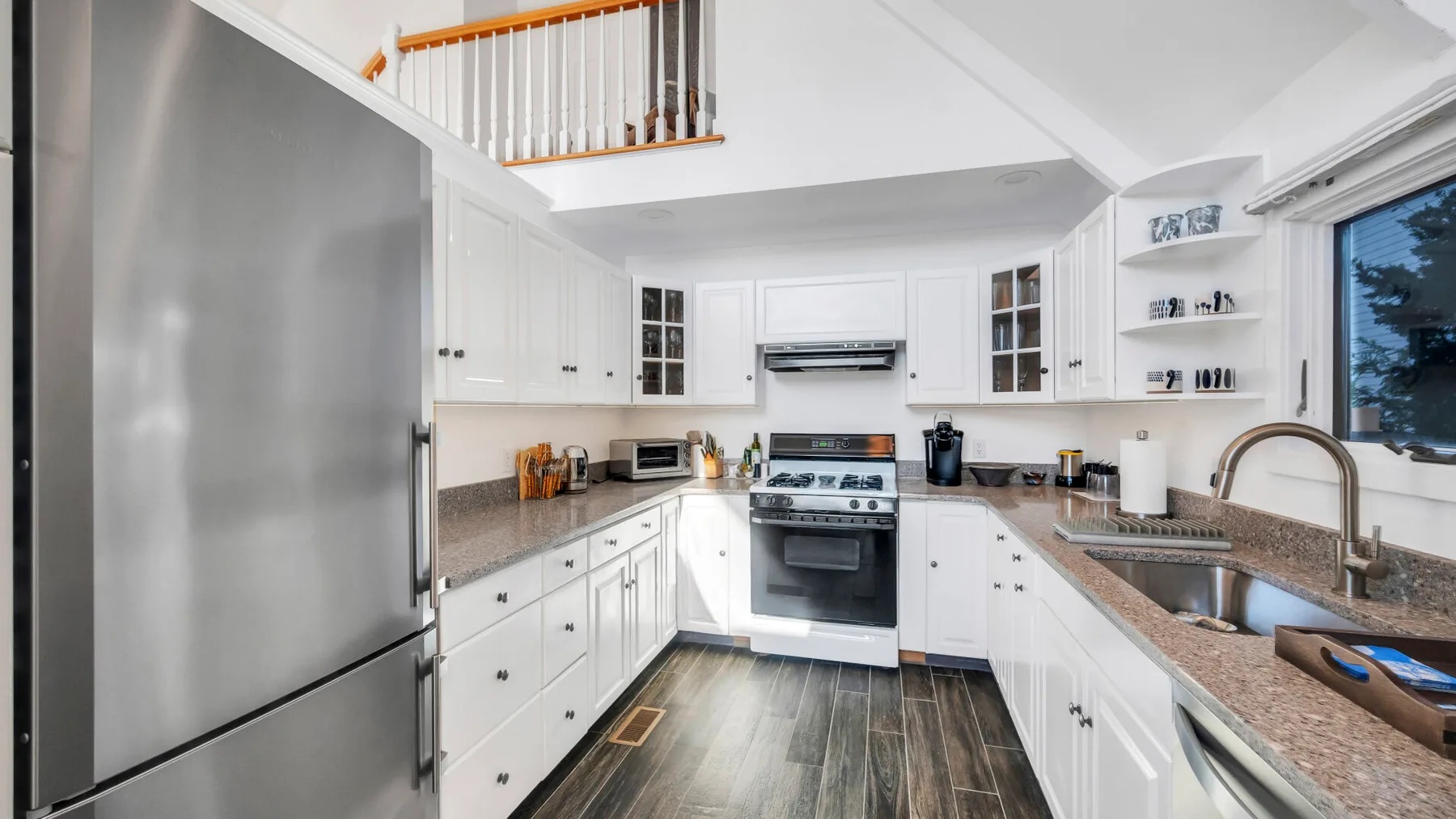 Una cocina luminosa con gabinetes blancos, una estufa y una encimera larga.
