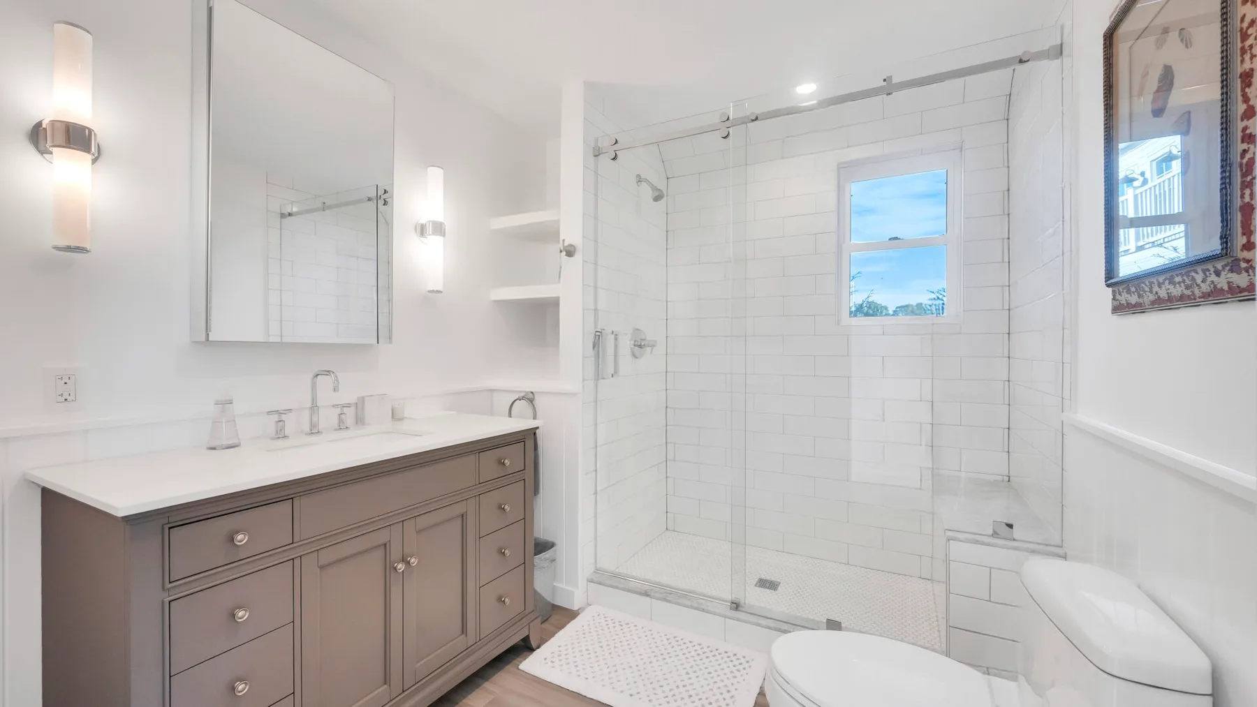 Un baño luminoso con lavabo, espejo y ducha de vidrio.
