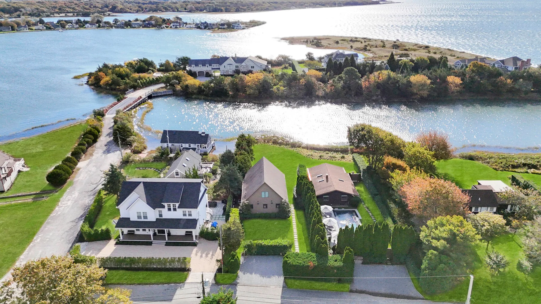 An aerial view of homes beside a winding waterway and green lawns.