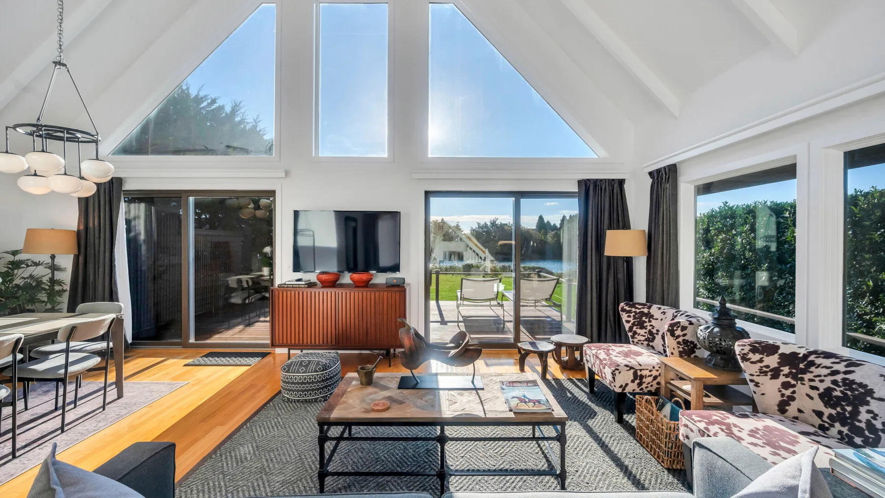 Una sala luminosa con grandes ventanas, una zona de estar y un televisor.