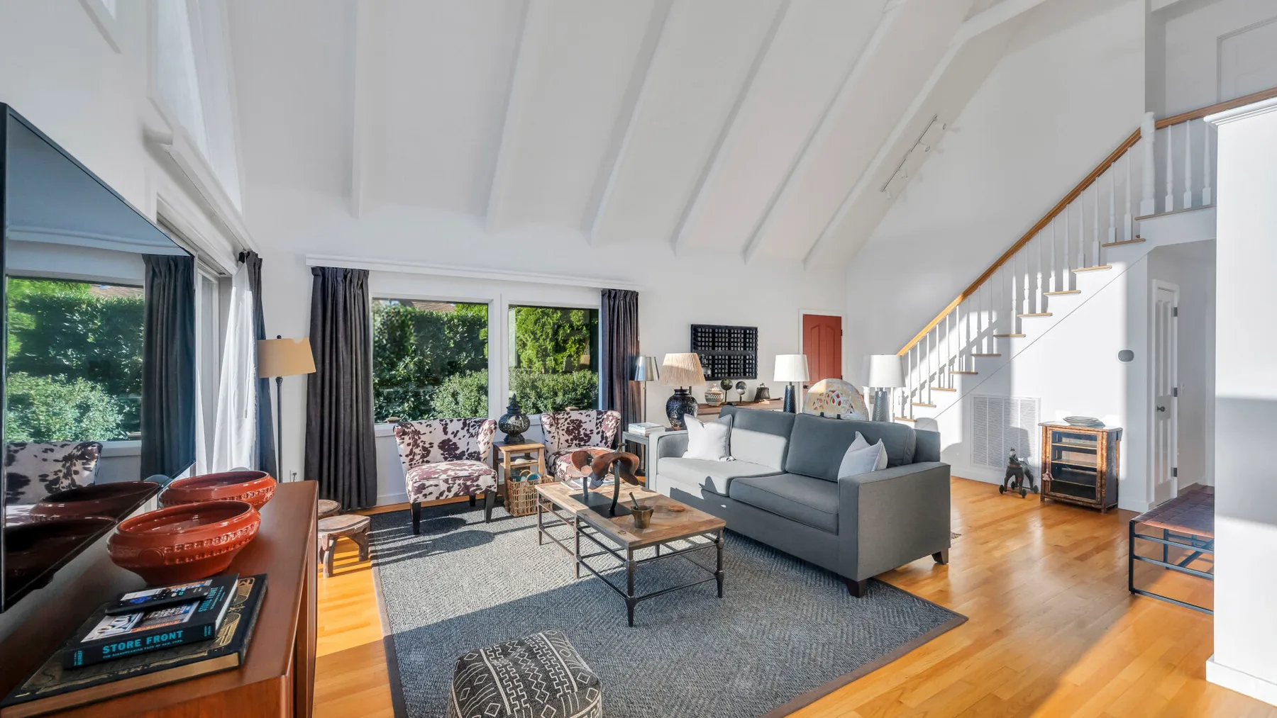 A bright living room with seating, a coffee table, and large windows.