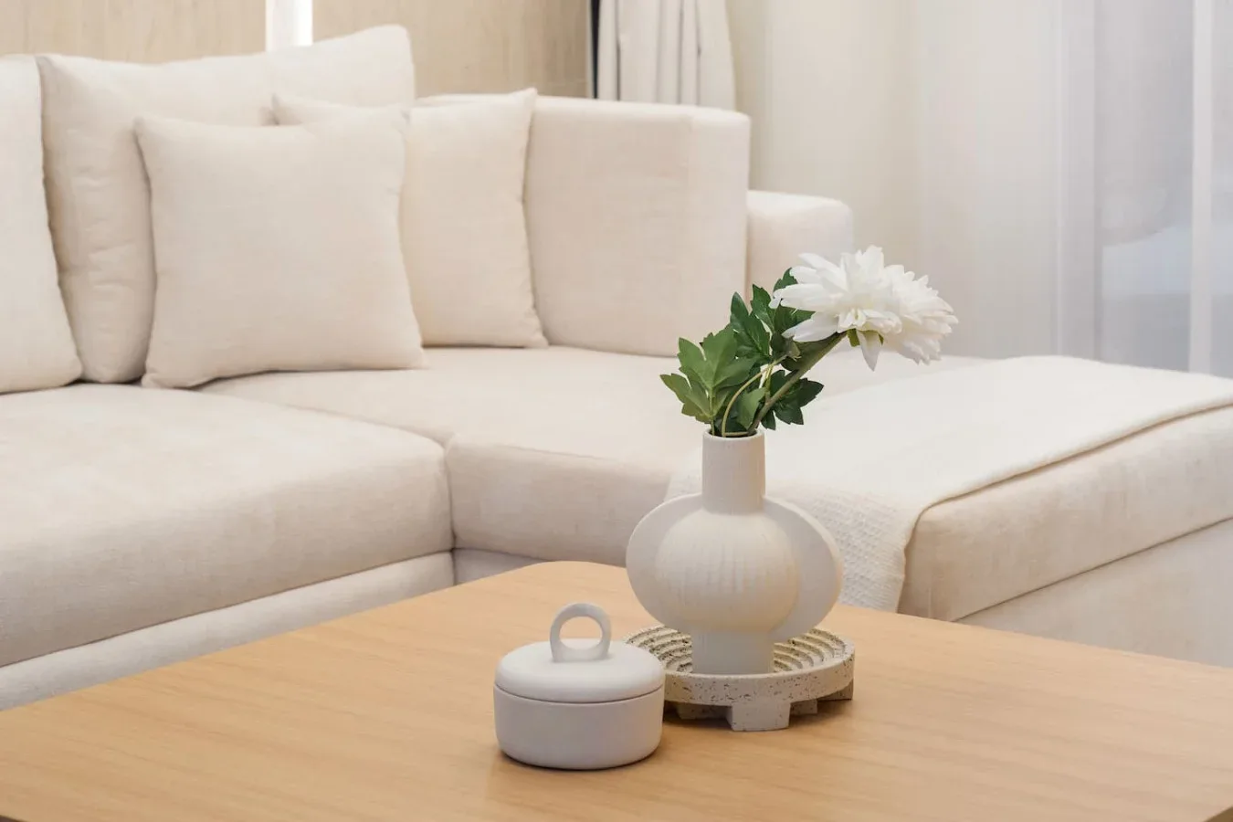 Una sala luminosa con asientos color crema y flores sobre una mesa de centro.