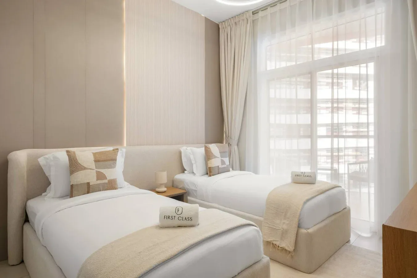 Un dormitorio luminoso con dos camas junto a una gran ventana con cortinas.