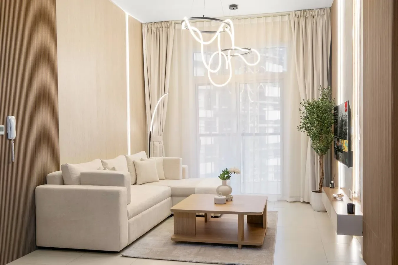 Una sala luminosa con asientos claros, una mesa de centro y cortinas largas.