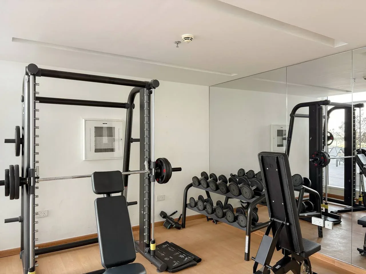 Un gimnasio con equipo de pesas y una pared con espejo.