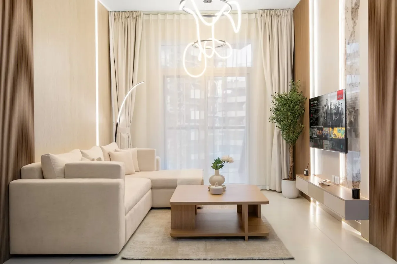 Una sala luminosa con asientos claros, una mesa de centro y cortinas largas.