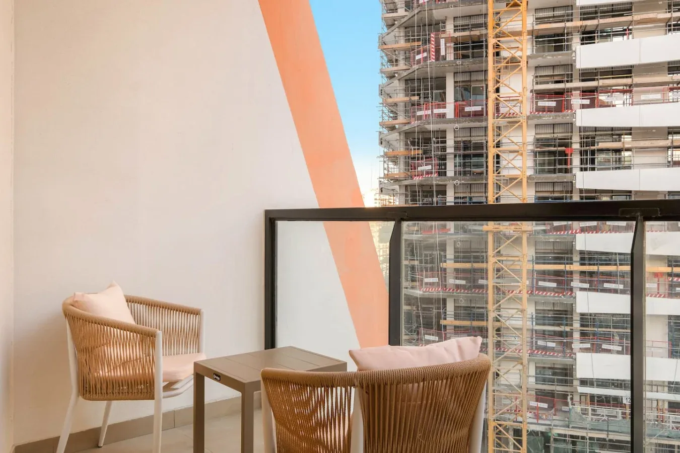 Una zona de estar en un balcón da a un edificio en construcción.