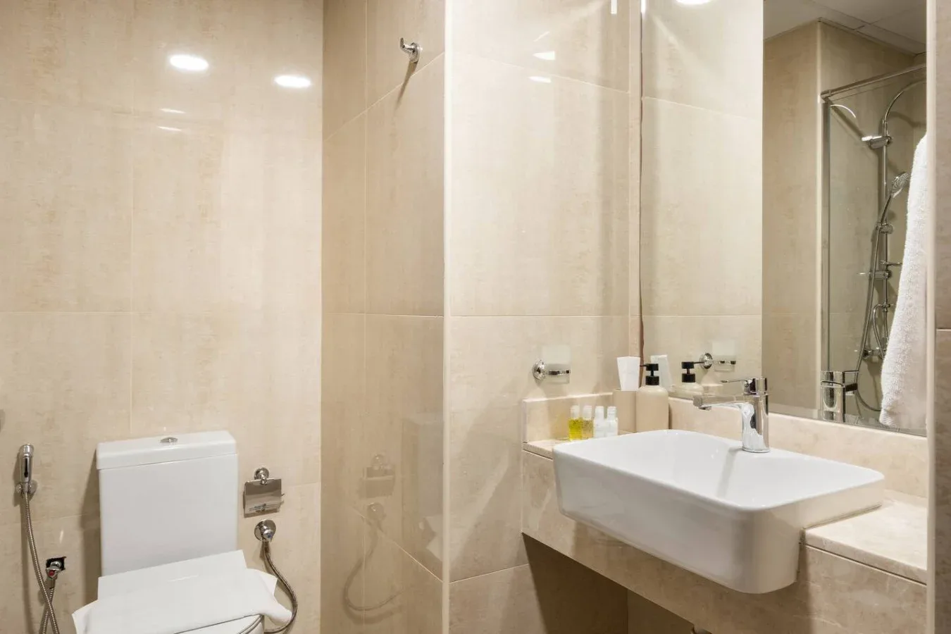Un baño alicatado con lavabo de pared y una ducha con mampara de vidrio.