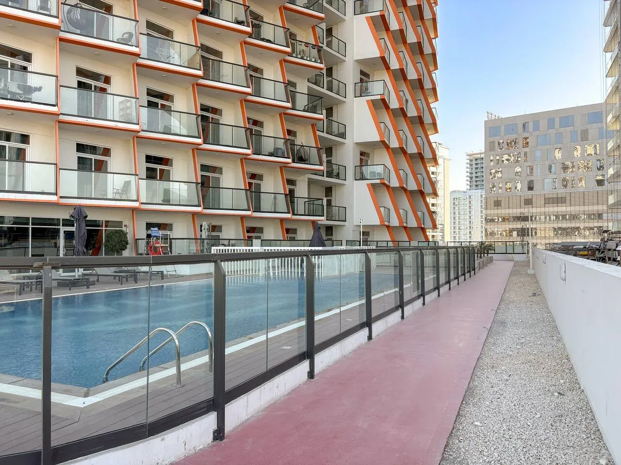 Una piscina al aire libre junto a un edificio moderno y un pasillo.