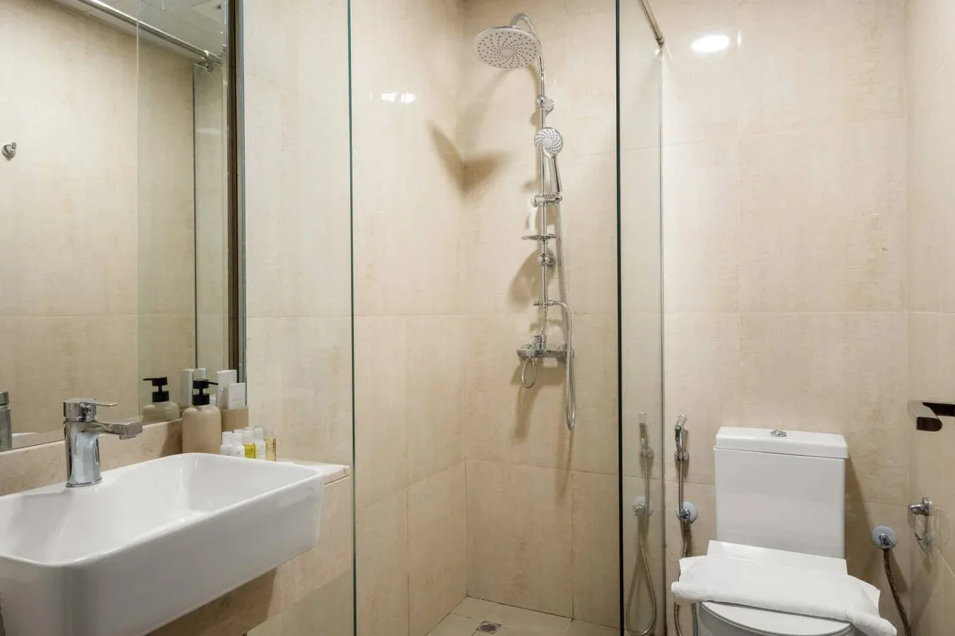 Un baño con azulejos, lavabo, inodoro y ducha montada en la pared.