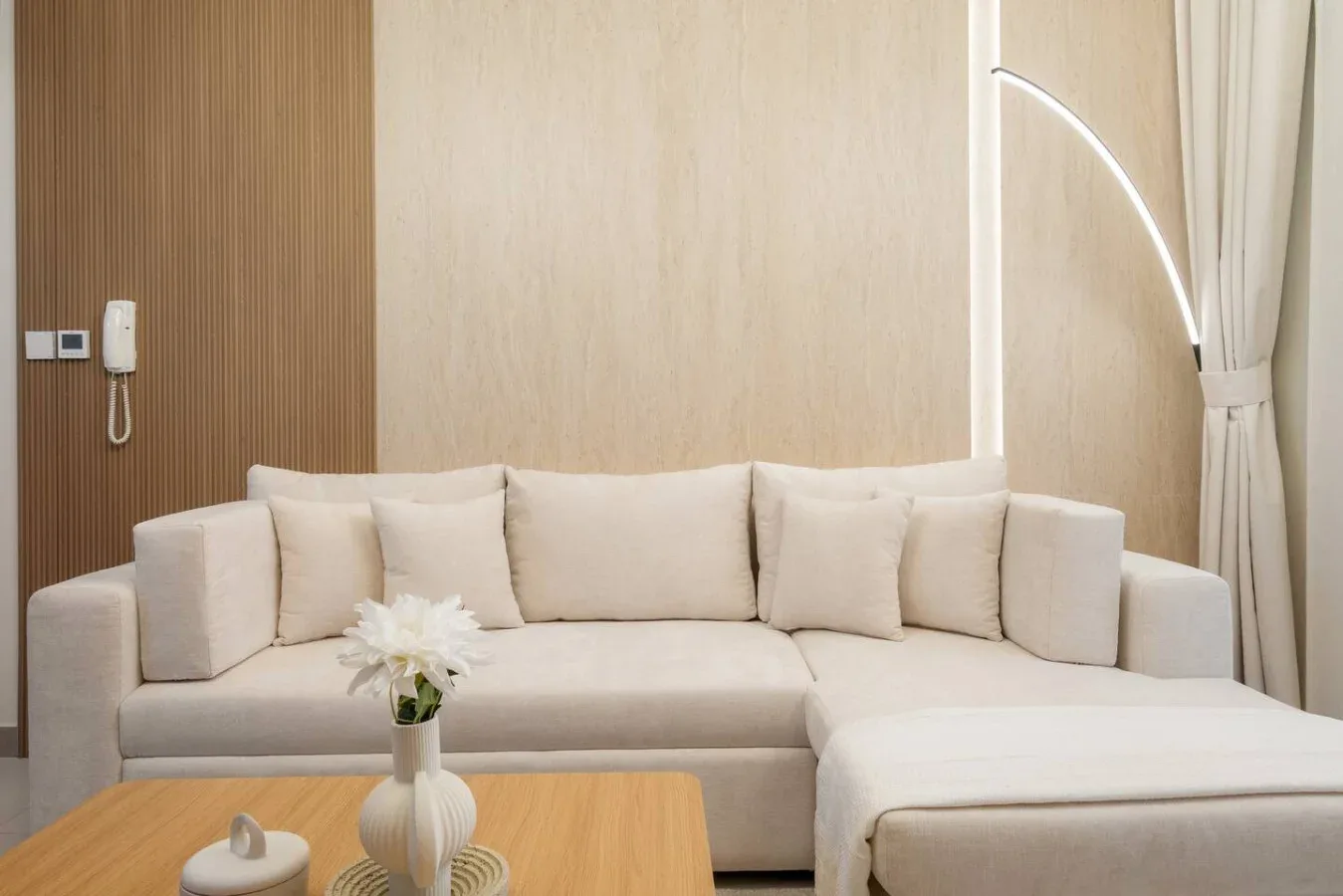 Una sala luminosa con un sofá seccional color crema y una mesa de centro de madera.