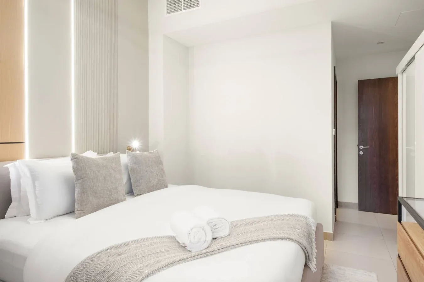 Un dormitorio luminoso con una cama bien tendida y toallas dobladas.