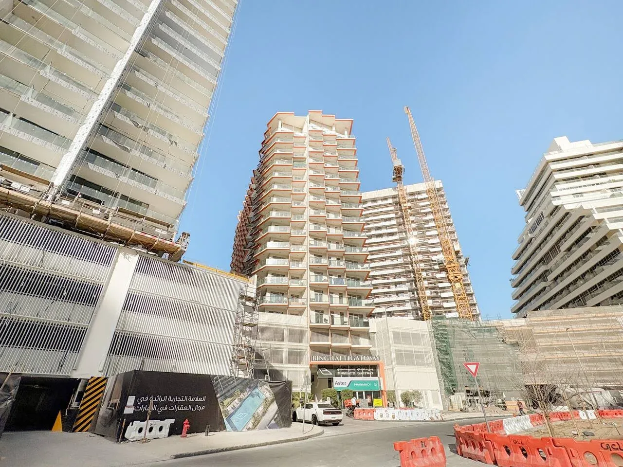 Edificios altos y una grúa de construcción se alzan sobre una obra junto a la calle.