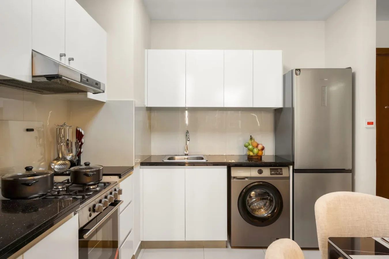 Una cocina moderna con armarios blancos, un refrigerador y una lavadora.