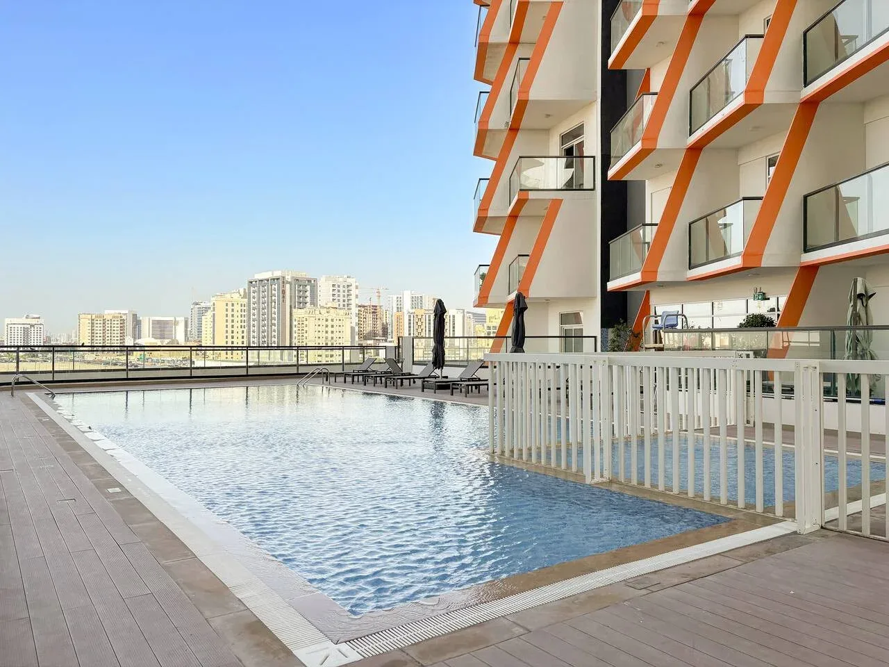 Una piscina al aire libre junto a un edificio de apartamentos moderno.