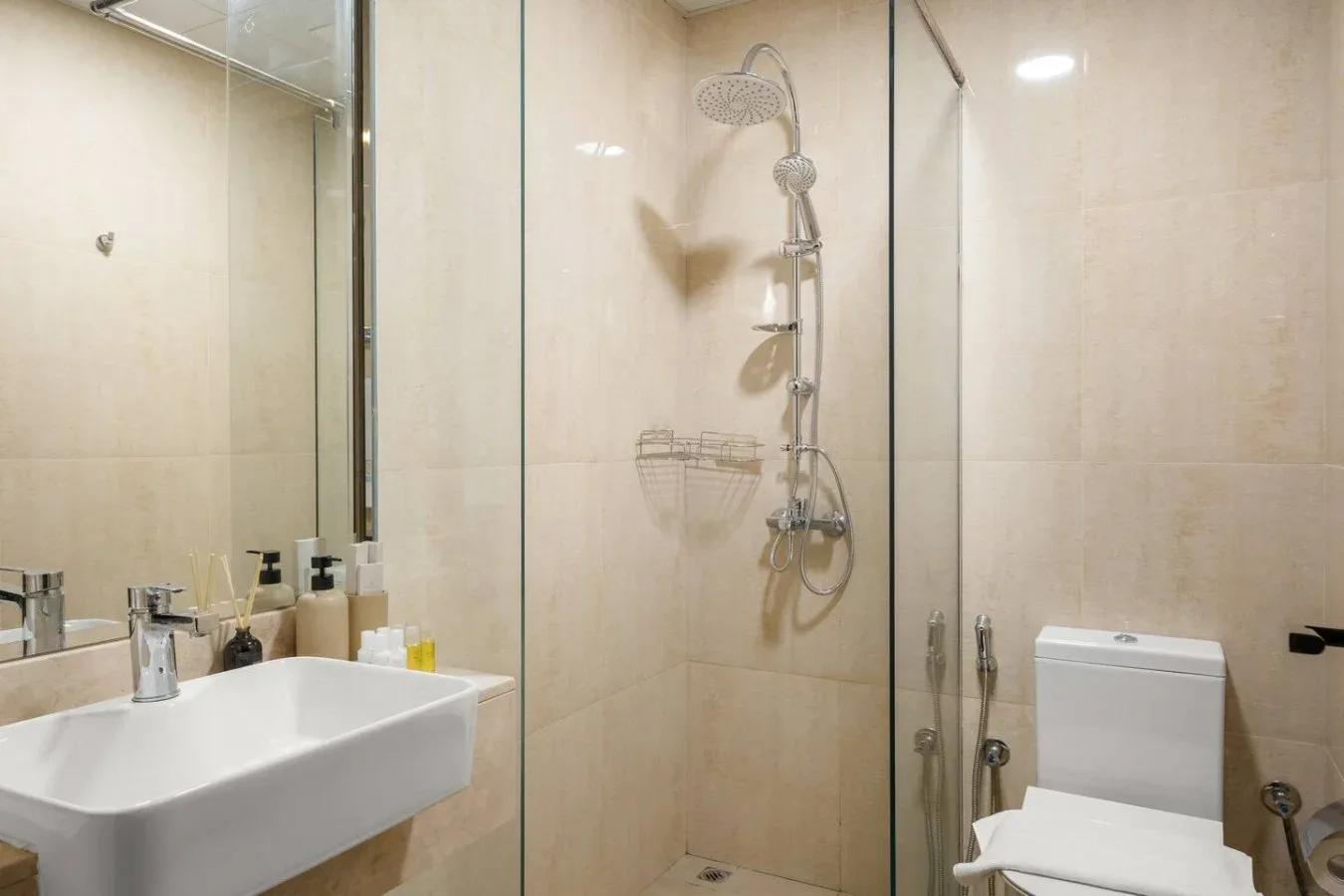 Un baño con lavabo y una ducha con mampara de vidrio.