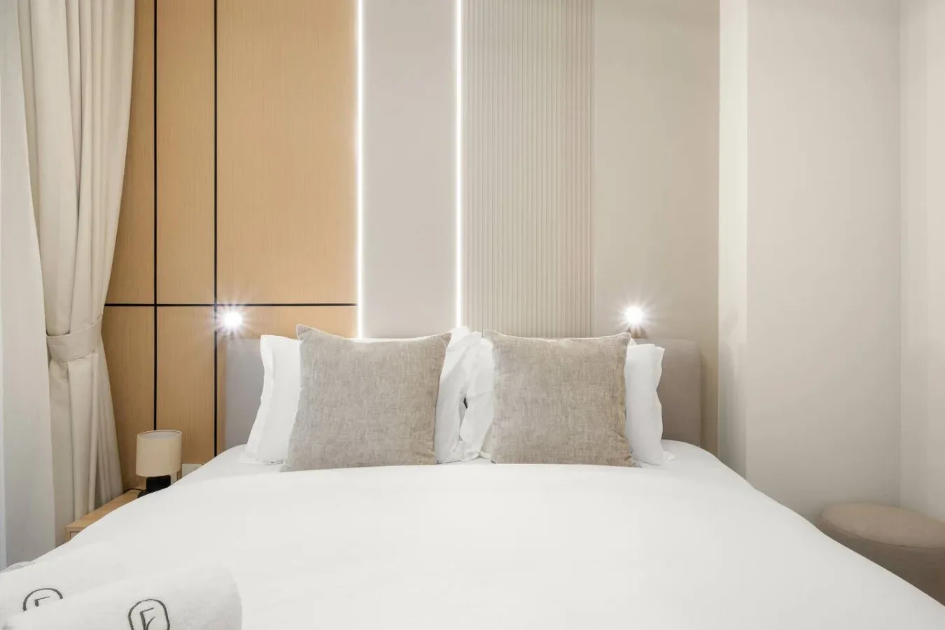 Un dormitorio con una cama tendida y almohadas claras.