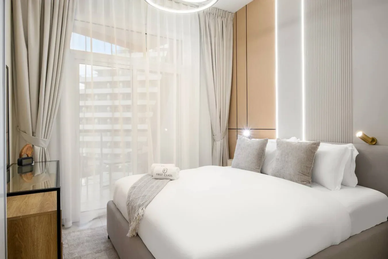 Un dormitorio luminoso con una cama bien tendida y cortinas translúcidas en la ventana.