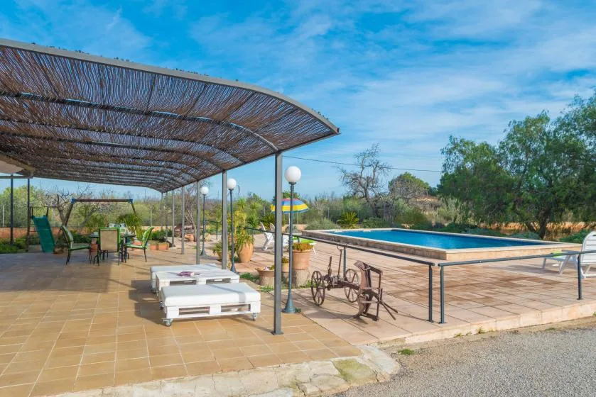 Un patio embaldosado con una zona de estar sombreada y una piscina al aire libre.