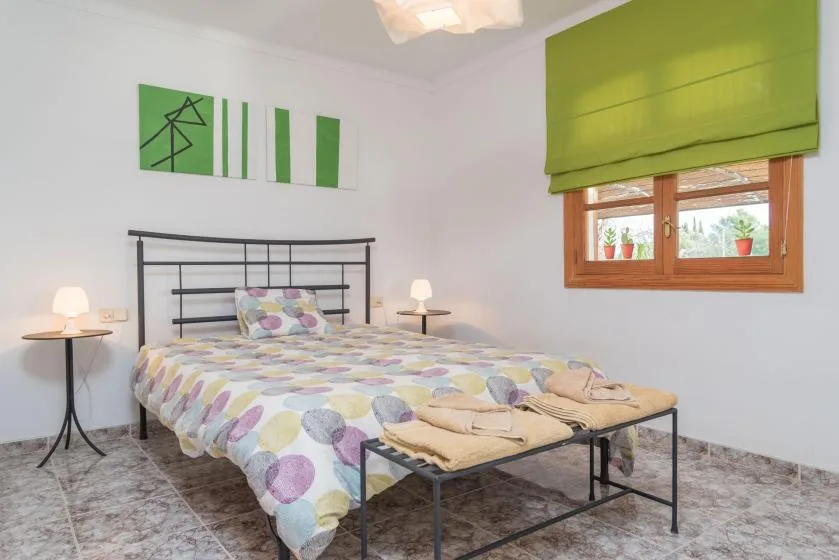 Un dormitorio con una cama cubierta con ropa de cama estampada y una ventana con cortina verde.