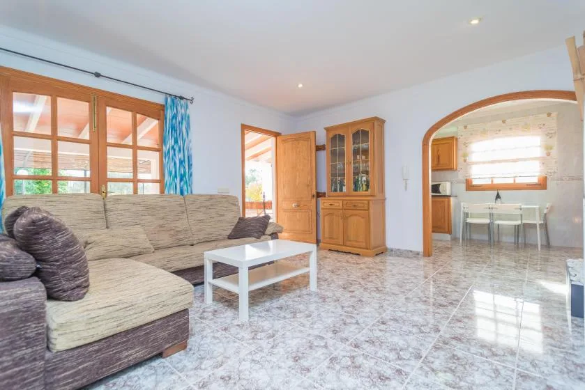 Una sala luminosa con asientos, una mesa de centro y un arco que da a la cocina.