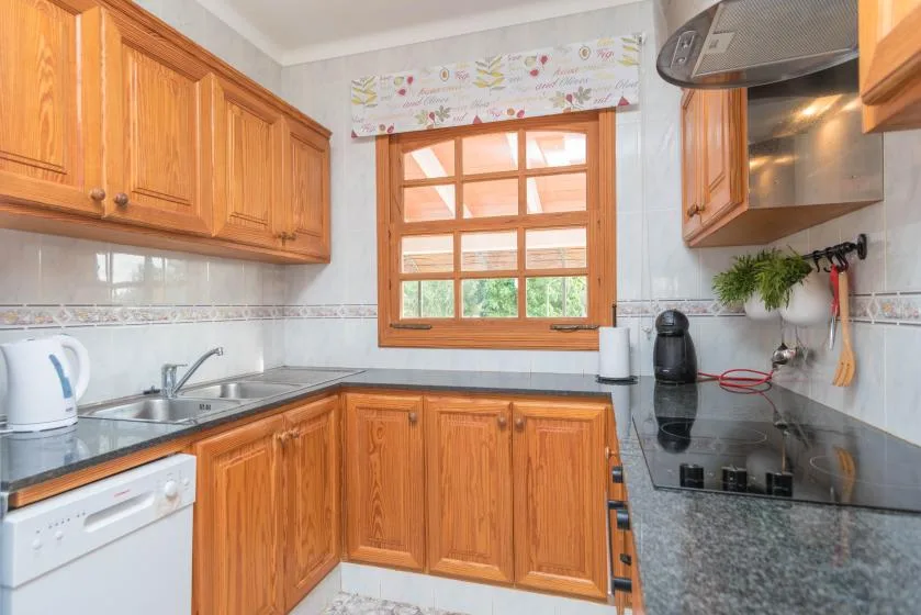 Una cocina con gabinetes de madera, una encimera y una ventana sobre el fregadero.