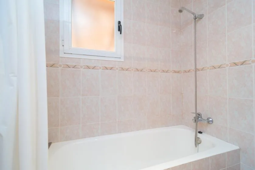 Un baño alicatado con bañera, ducha y ventana.