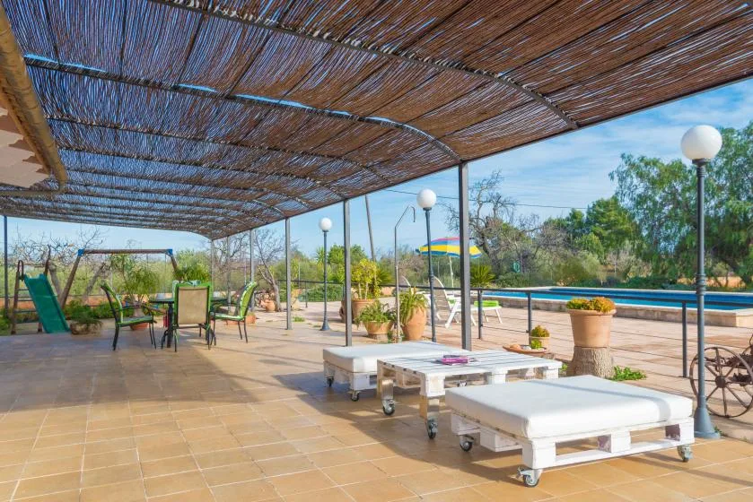 Un patio exterior sombreado con asientos de descanso da a una piscina.