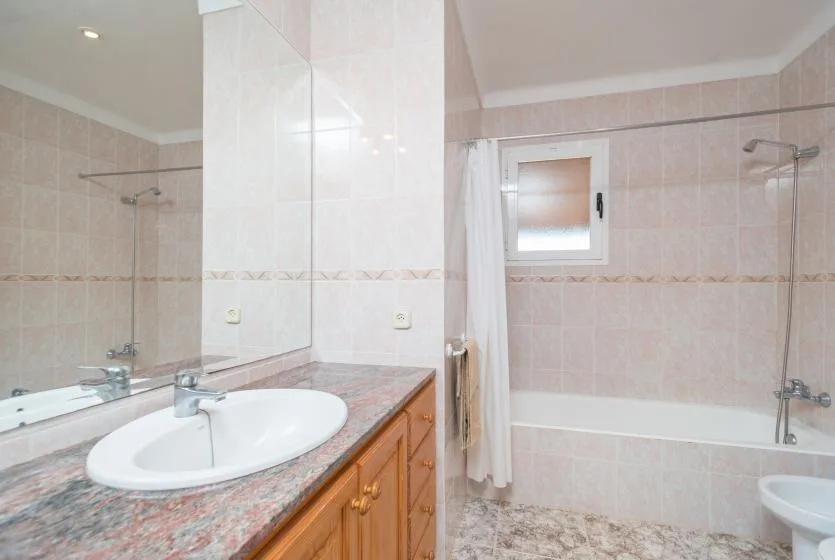 Un baño alicatado con bañera, ducha y lavabo.