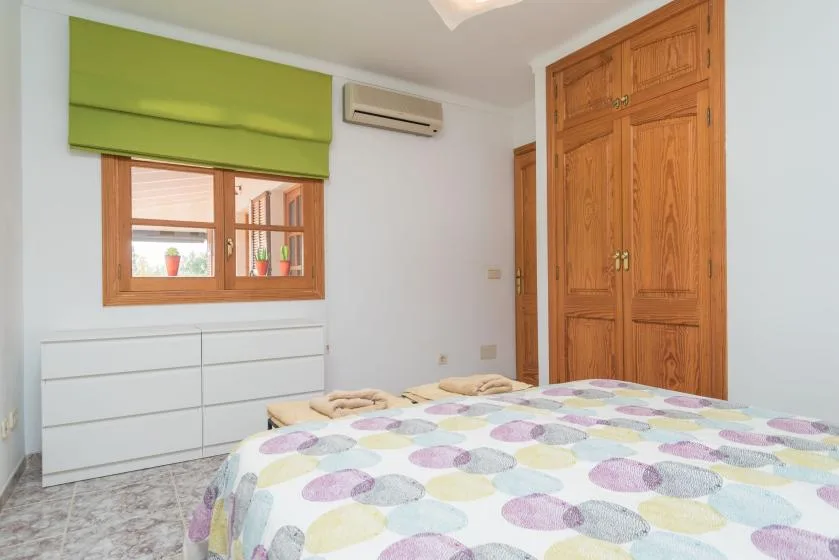 Un dormitorio con una cama cubierta con una colcha de colores y estampados.