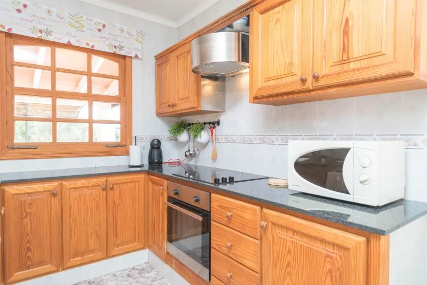 Una cocina luminosa con armarios de madera, una encimera y un microondas.