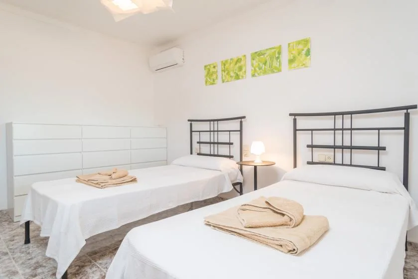 Un dormitorio luminoso con dos camas y toallas dobladas.